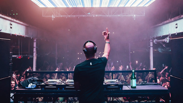 Party all night at Printworks. Credit: Printworks London. Image courtesy of Printworks London. DJ at the decks in front of a crowd at Printworks London