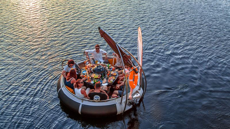 A group of young people cruising along the Thames while having lunch onboard a Skuna Boat on a summer's day.