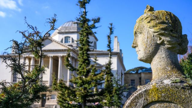 Explore 18th-century British architecture at Chiswick House and Gardens. Image courtesy of Luke Bachelor PR. A statue stands beside the grand Chiswick House in London.