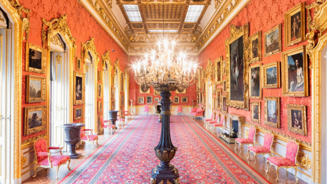 long red open hallway with lavish gold decor, framed pictures on the wall and a traditional light feature