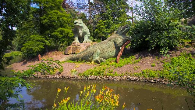 Two large model dinosaurs positioned by the edge of a pond in Crystal Palace Park.