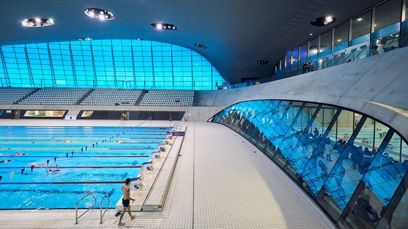 Visit the London Aquatics Centre in Queen Elizabeth Olympic for a revitalising dip. Credit: Everyone Active. Image courtesy of Everyone Active. Windows and seats surround the large swimming pool at the London Aquatics Centre