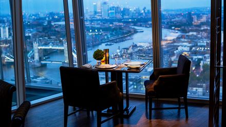 A table and chairs with a nightime view of Tower Bridge and the River Thames. Image courtesy of Shangri-La The Shard, London.
