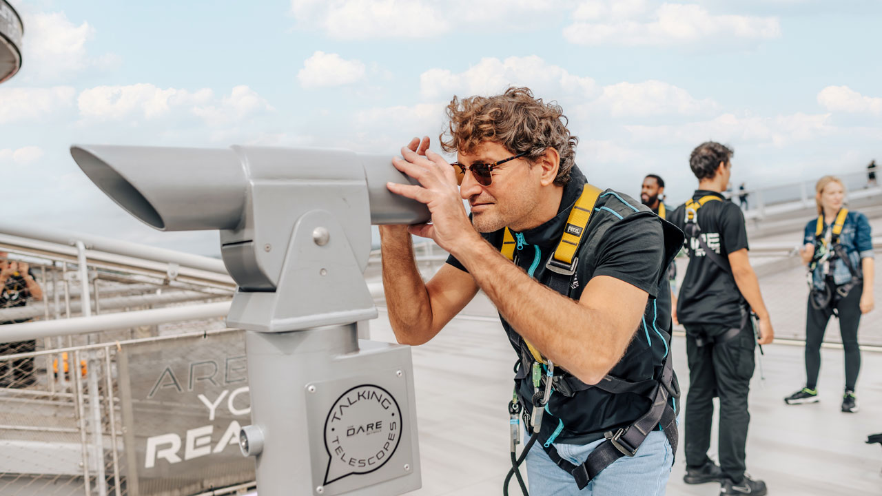 Enjoy views of Tottenham Hotspur Stadium and north London when taking on The Dare Skywalk. © visitlondon.com/Michael Barrow A man is observing the panorama from the top of Tottenham Hottspur stadium through a binocular.