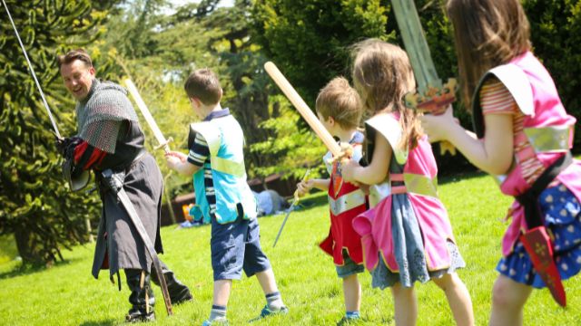 Learn how to use a sword at Warwick Castle. Image courtesy of Golden Tours. Children are shown how to use a sword by a knight at warwick castle.