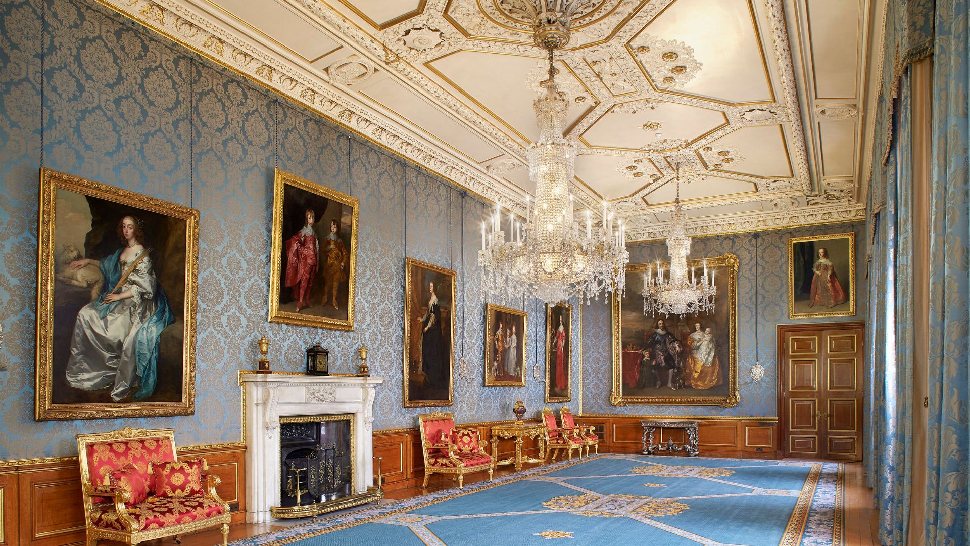 Marvel at the opulence of the Queen's Gallery at Windsor Castle. © Royal Collection Enterprises Limited 2025 | Royal Collection Trust. Photo credit: Peter Smith A grand room at windsor castle with blue carpet, sparkling chandeliers and historic paintings.