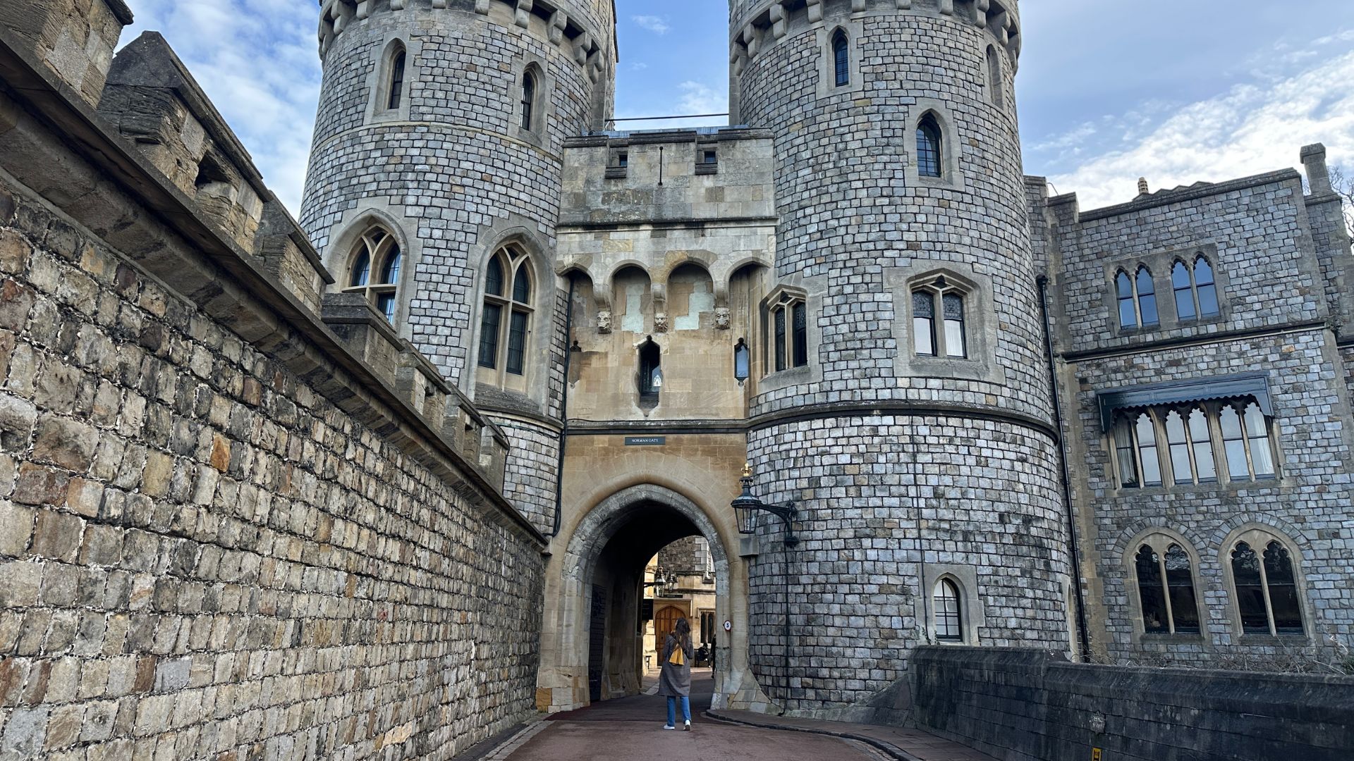 Walk through the historic courtyards of Windsor Castle. © Visit London/Kirstine Spicer A woman in a brown coat and yellow scarf stands looking up at windsor castle.