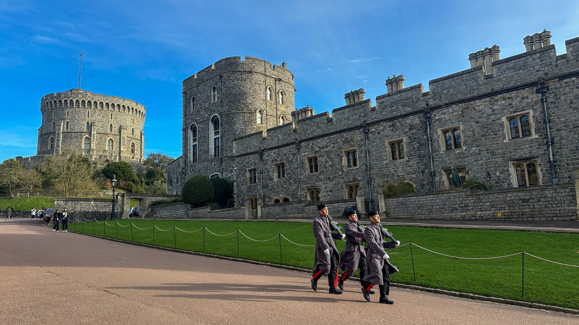 Grey guards make their way through the castle grounds. © Visit London/Kirstine Spicer Three guards walk through the grounds of windsor castle.