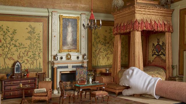 A hand picks up furniture in the queen marys dolls house at windsor castle.