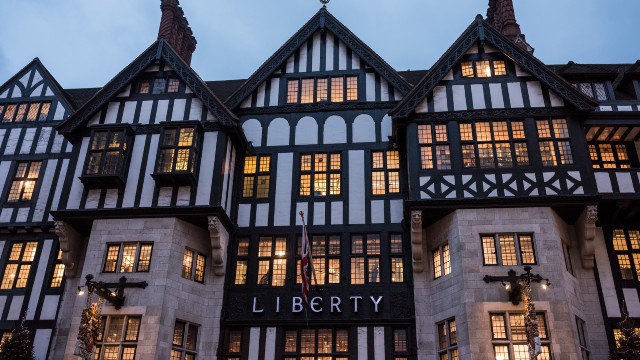 Liberty London. ©Ben Pipe/visitlondon.com. The exterior of Liberty London, a large department store with a black and white mock Tudor exterior and illuminated windows.