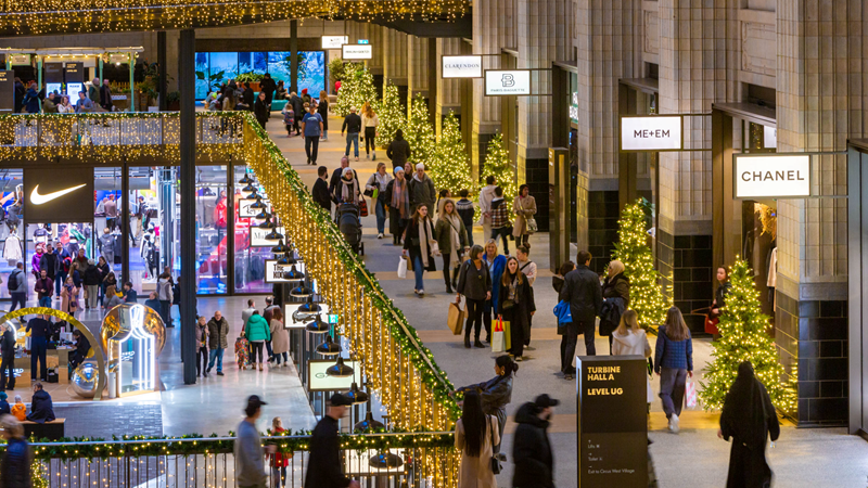 Find some of the best retailers in one place at Battersea Power Station in south London. Credit: Charlie Round-Turner. Image courtesy of Battersea Power Station. People walk around one of the many floors of shops inside Battersea Power Station adorned with Christmas decorations, with shop signs including Arcteryx, Reformation, SpaceNK and more lit up.