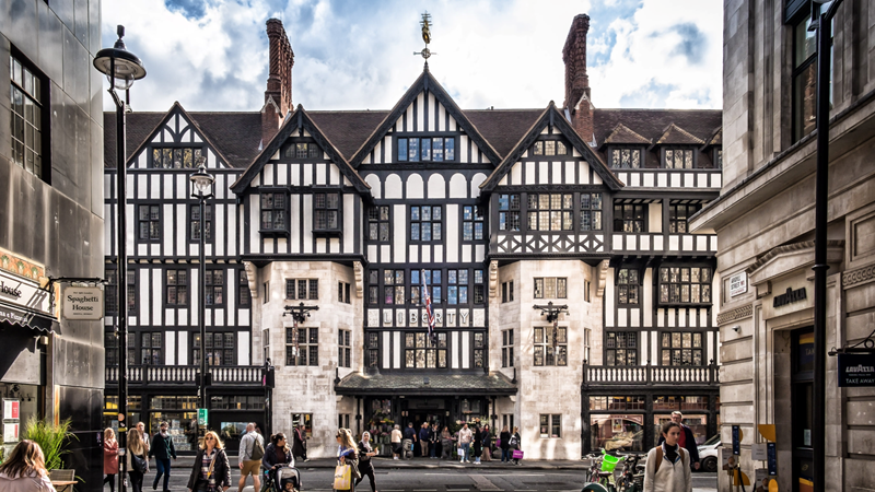 Liberty is a must-visit shopping spot on any London itinerary. Credit: Shutterstock. Image courtesy of Shutterstock. The front exterior of Liberty London in Soho with its iconic wooden beams, many windows and a busy street of pedestrians walking along the streets outside