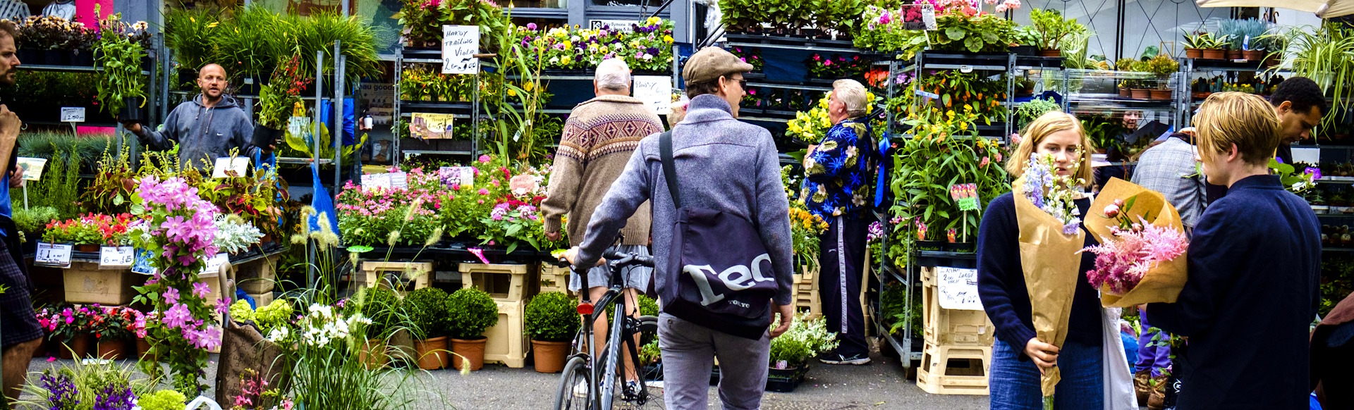 A man with a bicycle browses the flower-filled stalls of Columbia Road Flower Market.