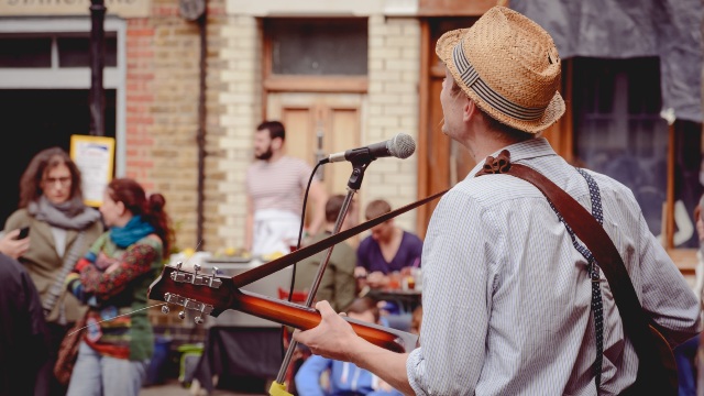 Street musician performing on Columbia Road. Image courtesy of Shutterstock / Paolo Paradiso. Street musician singing and playing the guitar to a small crowd on Columbia Road.