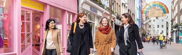 Four women chatting on Carnaby Street in London.