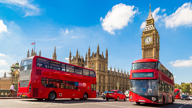 Big Ben and the Houses of Parliament © Shutterstock. Image courtesy of Shutterstock. Two red London buses pass in front of Big Ben and the Houses of Parliament on a sunny day.
