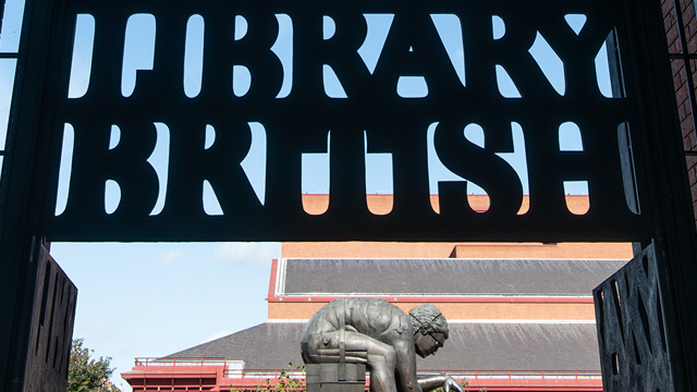 Black sign of the British Library with a sculpture in the background.