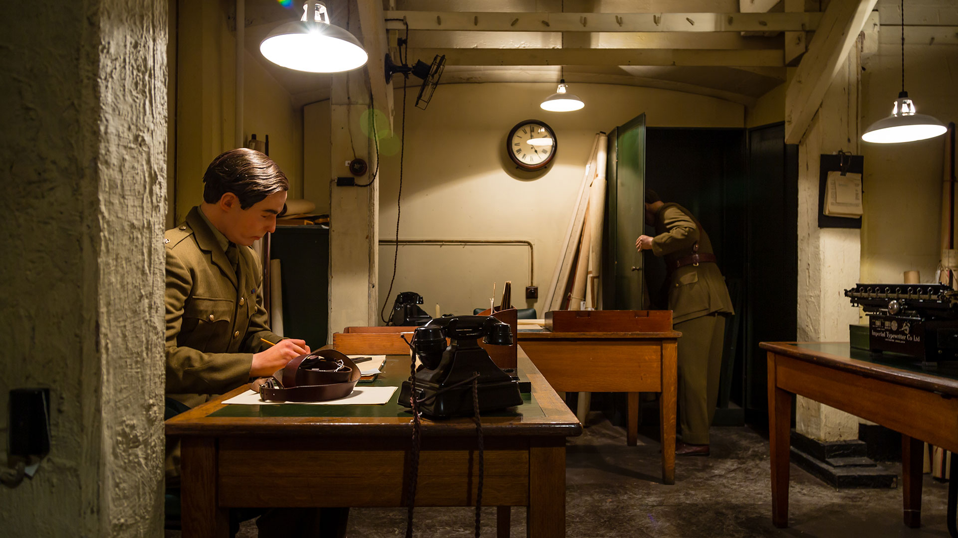Visit the Churchill War Rooms and immerse yourself inside the secret cabinets where Churchill and his team planned D-day. Image courtesy of Shutterstock. Underground bunker in the Churchill War Rooms, where a mannequin in a khaki army uniform sits at a table writing a report.