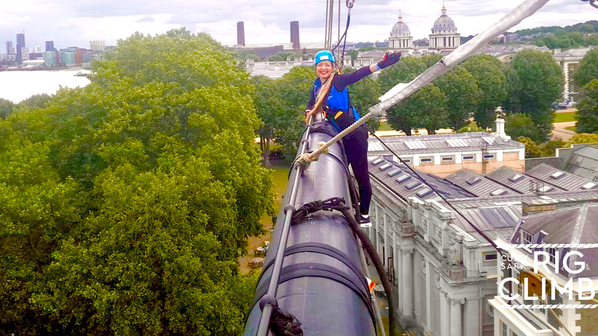 Feel the thrill of walking along the foot rope of the Lower Topsail Yard. Image courtesy of Wire & Sky. A woman standing on a thin foot rope and waviing from the Lower Topsail Yard.