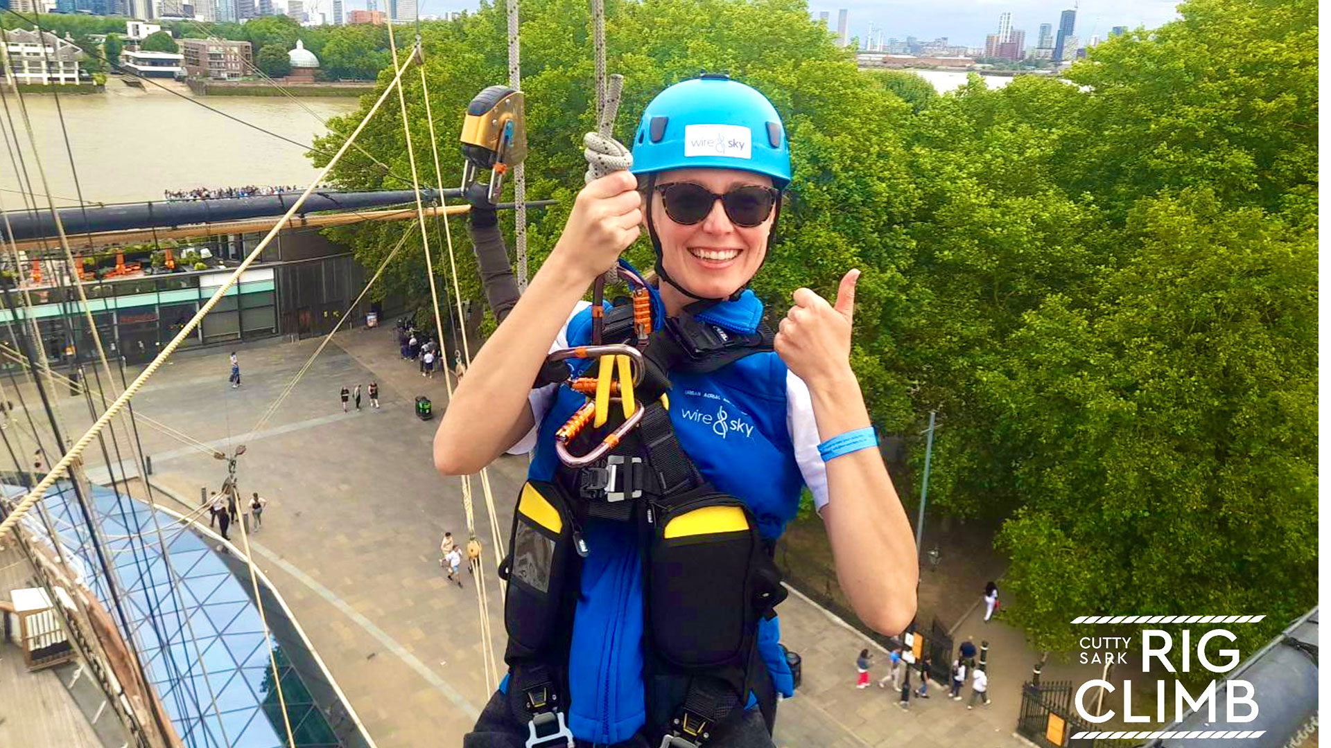 Experience a rare opportunity to climb the rigging of Cutty Sark before making an exhilarating zip line descent. Image courtesy of Wire & Sky. A smiling woman in climbing gear zip lining down the Cutty Sark.