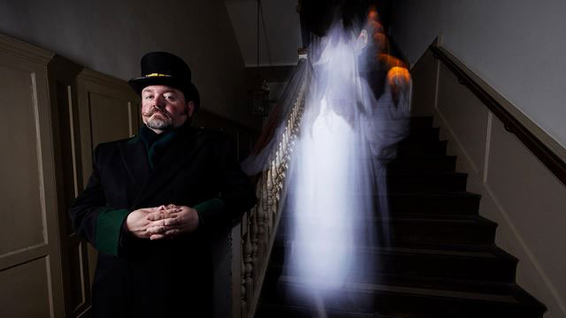 Historic hauntings at Hampton Court Palace. Image courtesy of Historic Royal Palaces. A warden stands with a ghostly apparition behind him