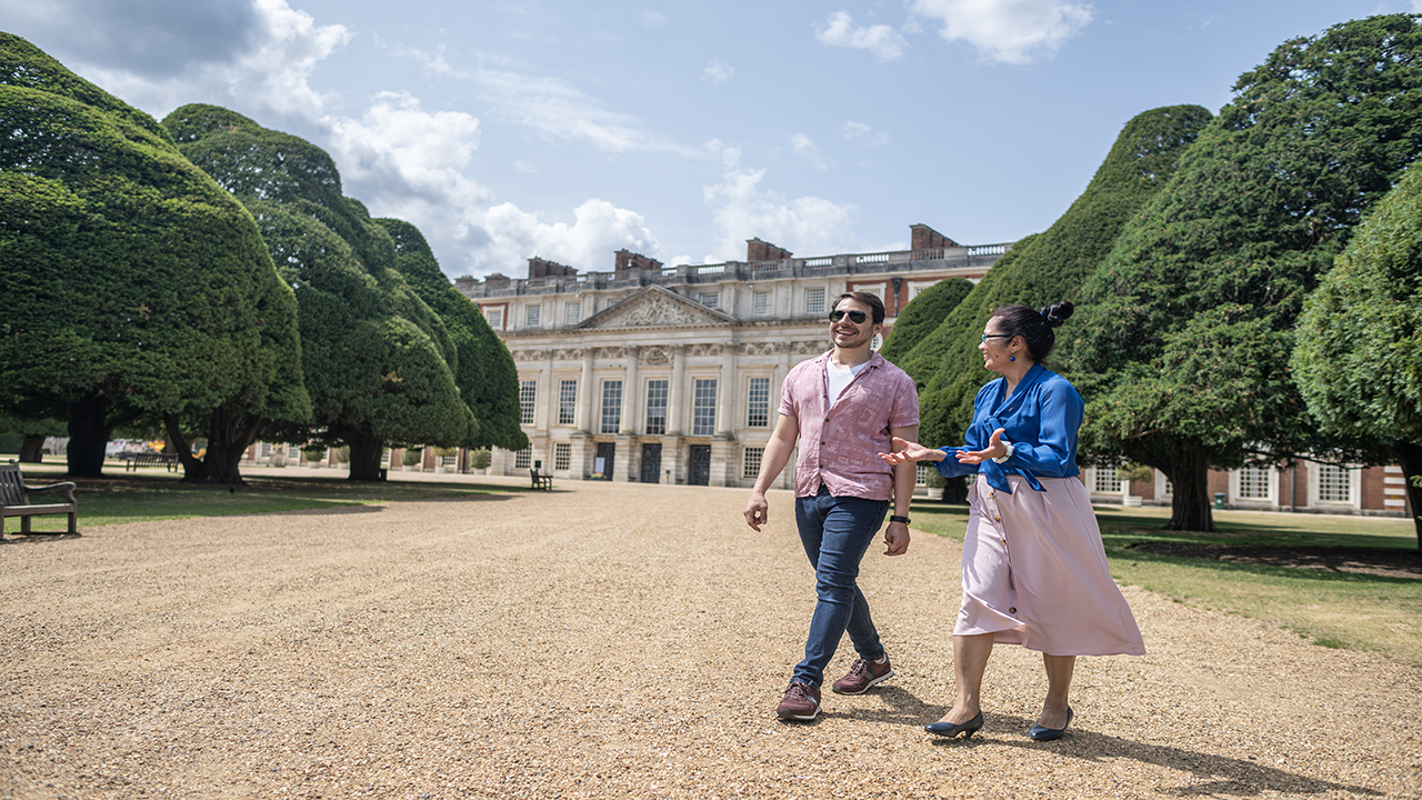 Stroll through Hampton Court Palace’s world-famous gardens, home to the oldest puzzle maze. © London & Partners/Michael Barrow. Two friends enjoying the sunny weather at Hampton Court Palace and strolling across its famous gardens.