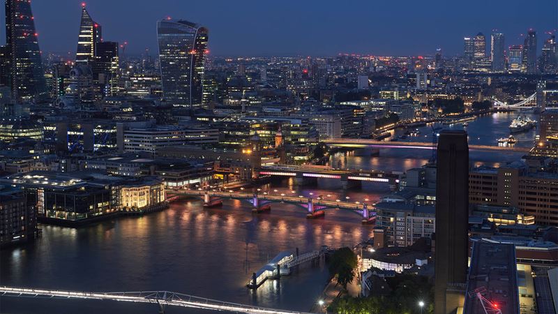 London bridges are lit up along the Thames at night with the skyline. 