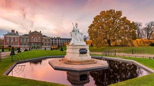 Queen Victoria statue in Kensington Gardens, with tree with autumn leaves, and Kensington Palace in the background