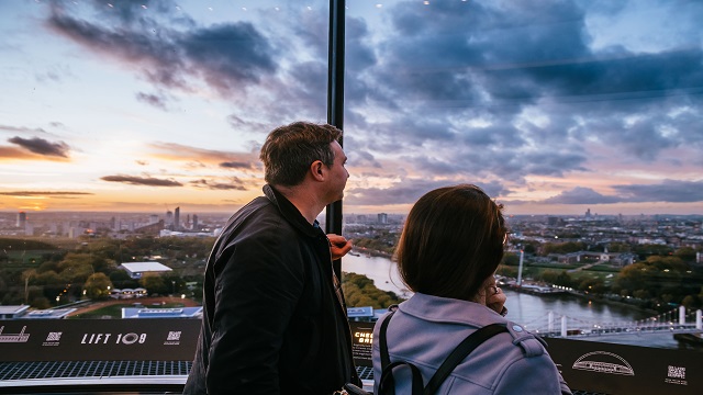 two people looking out through glass windows overlooking the London skyline and the river Thames