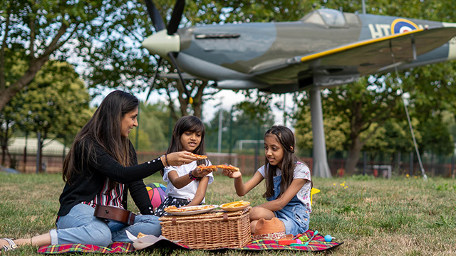 Three children sitting outside, playing together on the grass.