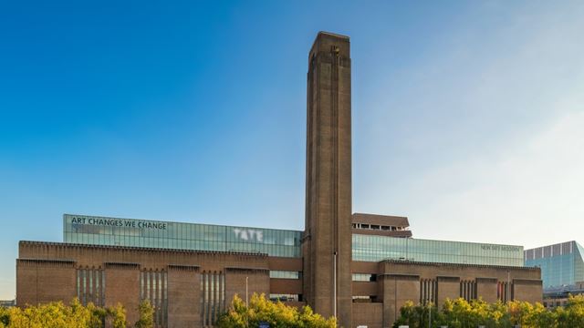 The magnificent chimney of the Tate Modern building against a blue sky.