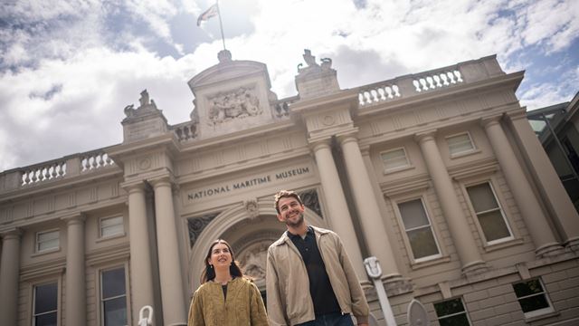 A man ad a woman are standing in front of the Maritime Museum in London.