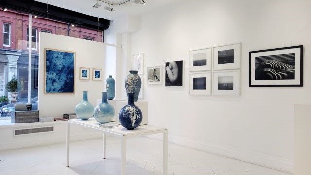 Blue sculptures and blue and black and white photographs on display at the Atlas Gallery in London.