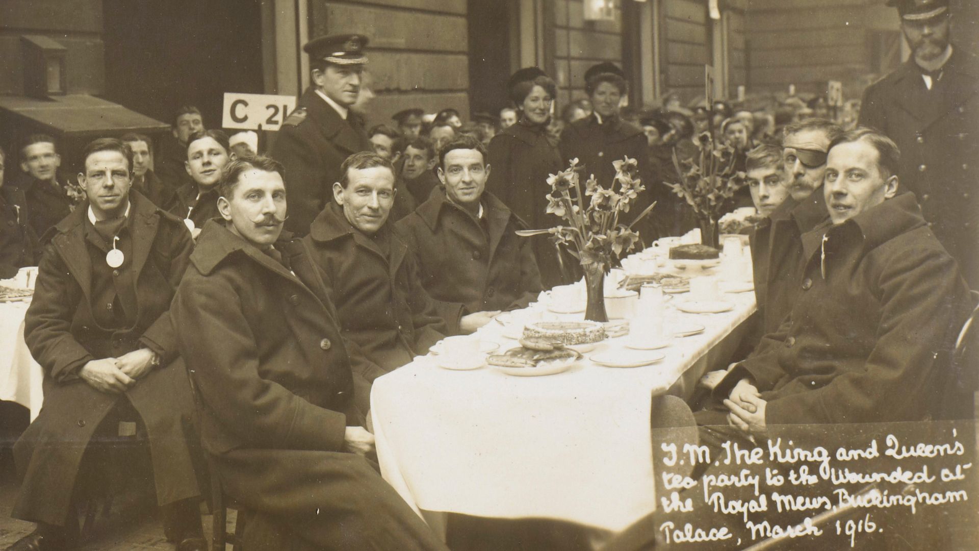 Archival image of King George V and Queen Mary’s tea party for wounded soldiers at the Royal Mews, Buckingham Palace, March 1916. © Royal Collection Enterprises Limited 2025 | Royal Collection Trust Vintage photo of wounded soldiers at a tea party hosted by the King and Queen at the Royal Mews during World War I.
