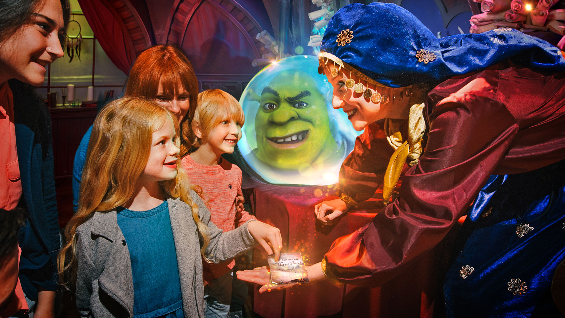 Head to Southbank and visit family favourite attraction Shrek's Adventure! London. © Merlin Entertainments 2025 A fortune teller, surrounded by children, reveals a glowing prophecy globe where Shrek’s face appears.