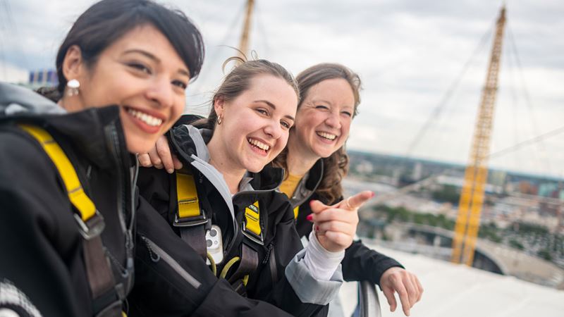 Get ready for an adrenalin-fuelled experience with Up at The O2 and enjoy incredible views over Greenwich. Copyright: London & Partners/Michael Barrow Three women are on the roof of the O2 arena looking out over London.