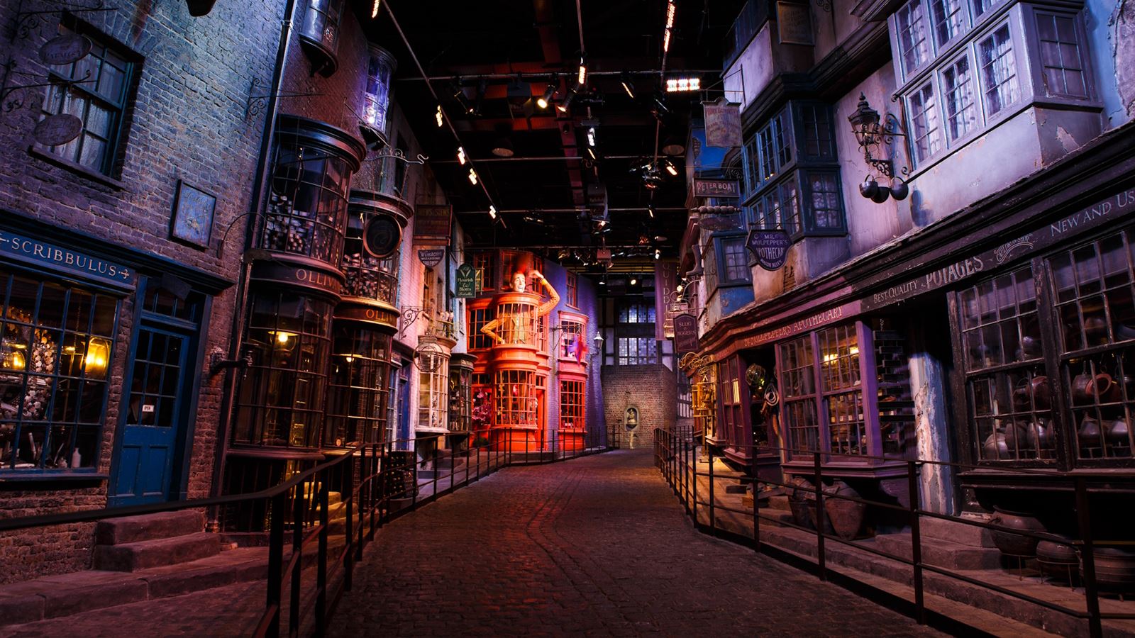 The set of Diagon Alley at the Warner Bros. Studio Tour in London, featuring empty and darkly lit alleyway with brick buildings and a red facade in the distance.