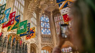 A woman takes a photo with her mobile phone of the Lady Chapel with its carved ceiling and stained glass windows.