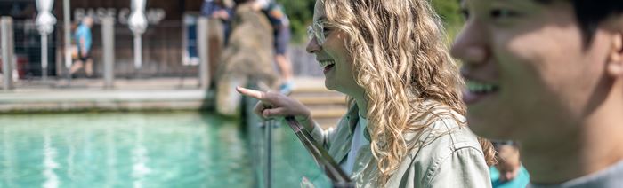 Two people lean over an aquarium home to penguins at London Zoo.