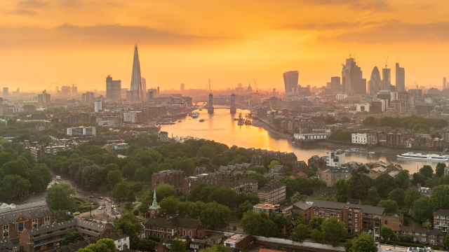 London skyline and river side while the sunset turns the sky orange.