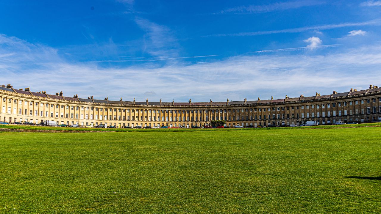 Wander along the Royal Crescent in Bath. Image credit: Unsplash/Sung Shin. A sweeping Georgian building in the shape of a crescent in bath.