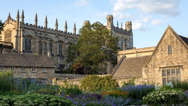 An old grand building surrounded by trees in christ church meadow in oxford.
