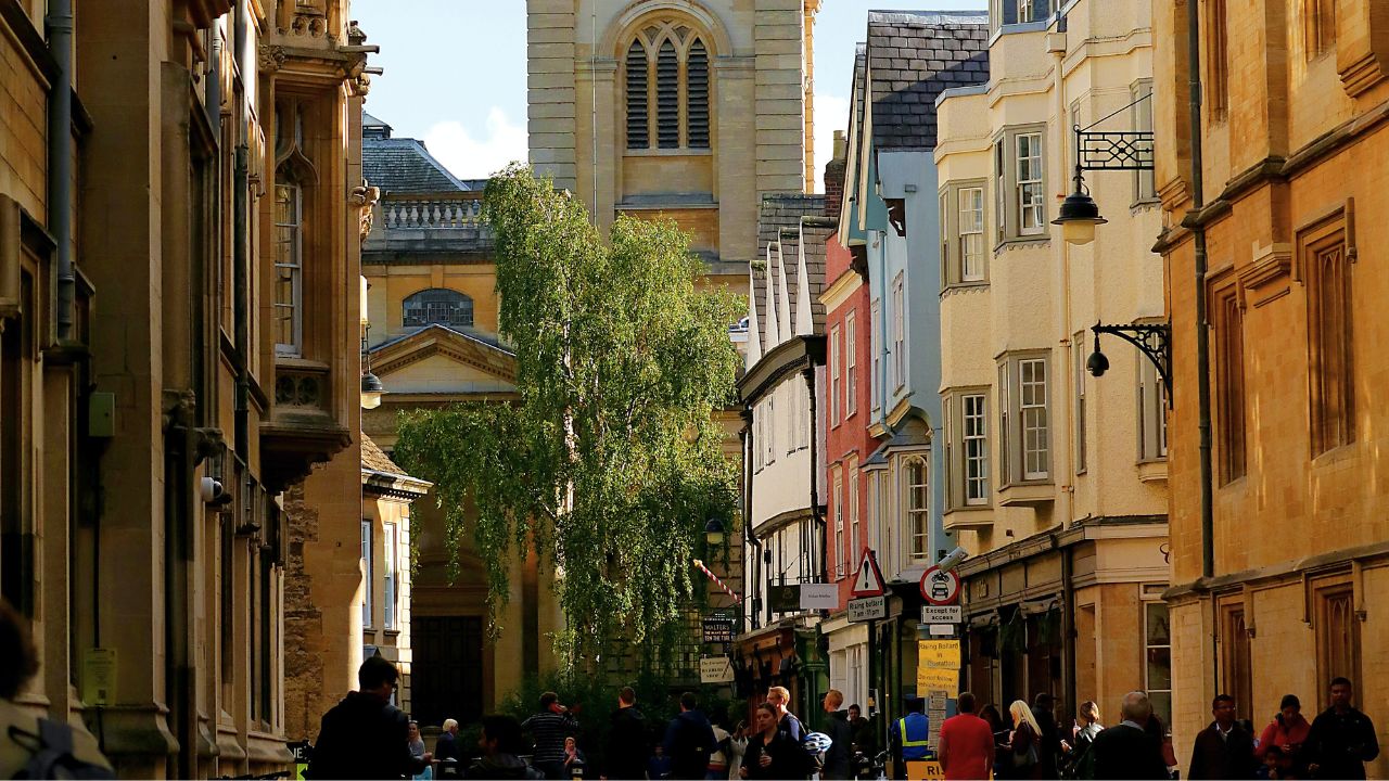 People walk along a sunny street in Oxford, UK.