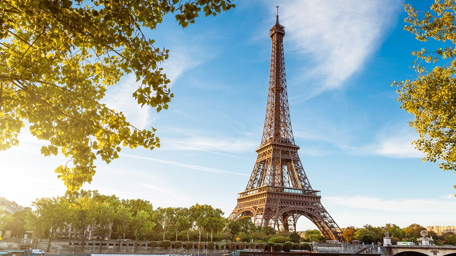 A view of the Eiffel Tower from across the Seine river on a bright day.