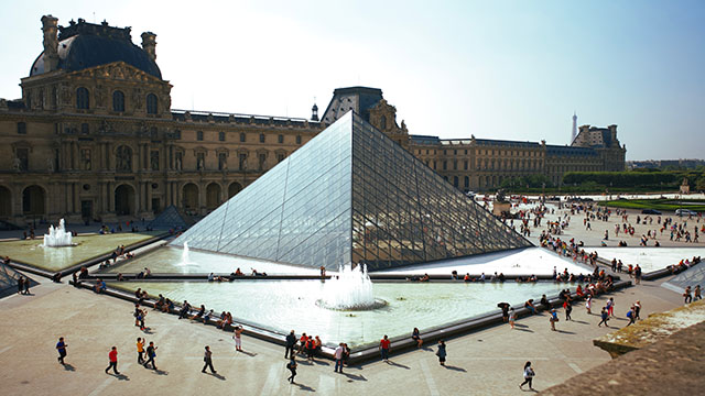 Le Louvre, one of the largest art collection in Paris. © Unsplash/Daniele D'Andreti View from above on the Louvre museum and its iconic glass pyramid with people walking by.