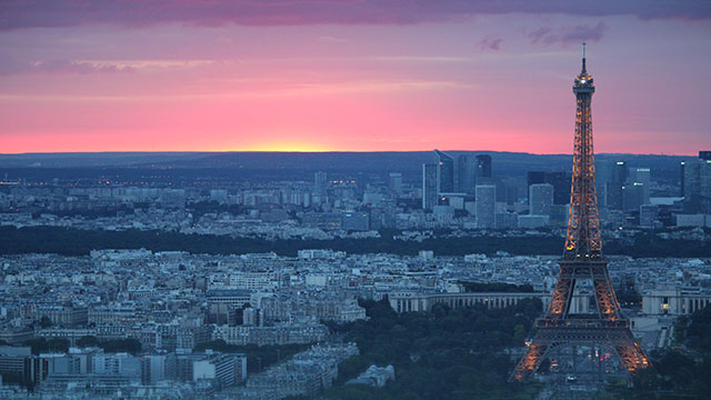View on the Eiffel Tower at sunset. © Unsplash/Alex Mustaros Panoramic view of Paris at sunset with the Eiffel Tower sparkling at night.