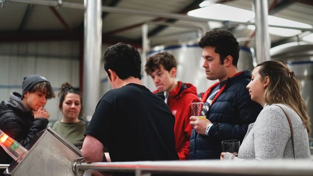 Taste a tipple or two at Brew York. Image courtesy of Brew York. A group of people stand together with a guide and try different beers in a york brewery,