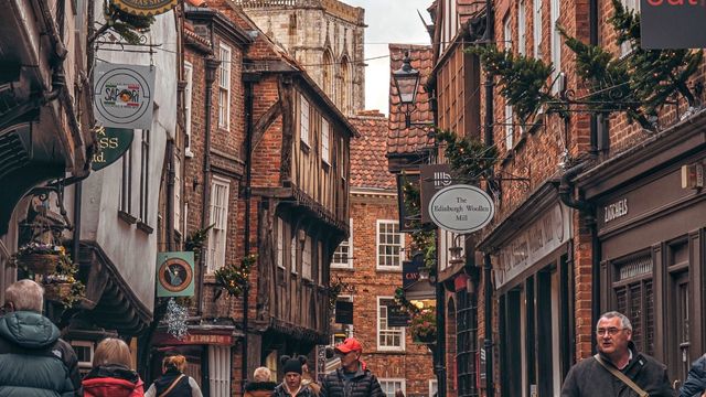 Wander the charming alleyways of The Shambles. © Unsplash/Hayden Pollen People walk among a narrow street in york with tower medieval buildings in the shambles district.