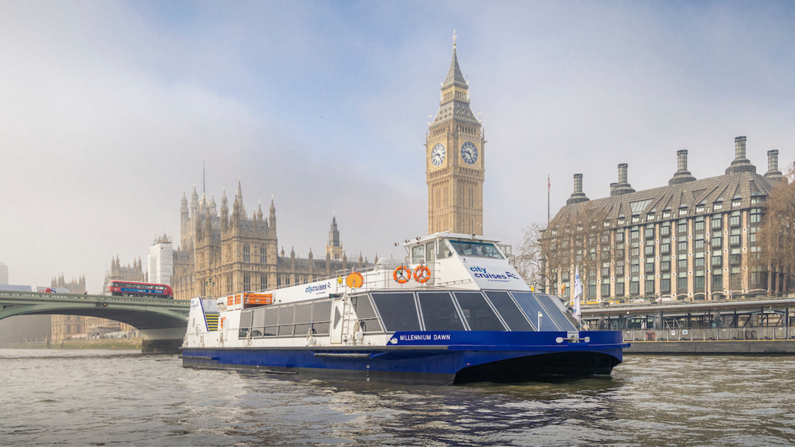A City Cruises boat on the river Thames with Big Ben and Westminster Bridge in the background