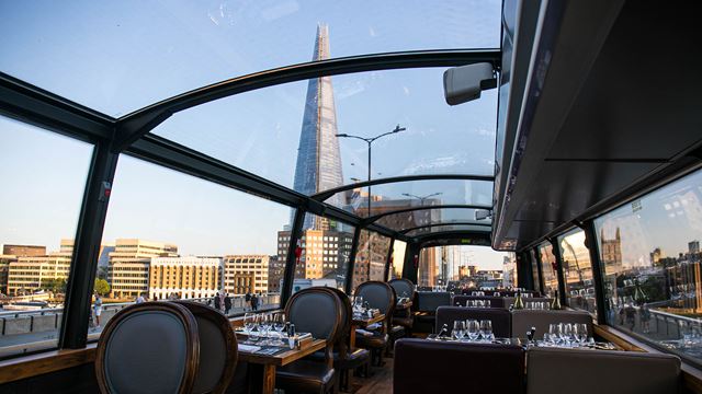 The Shard and the London skyline seen through the glass roof of a tour bus on a clear sunny day.
